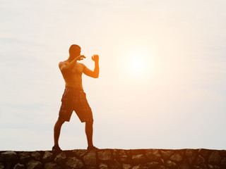 Young man practicing on the background of the sky, fighting