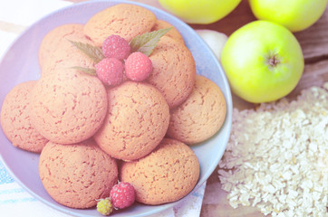 Oatmeal cookies with berry raspberries in a Cup of the green apples next to a bunch of flakes oatmeal