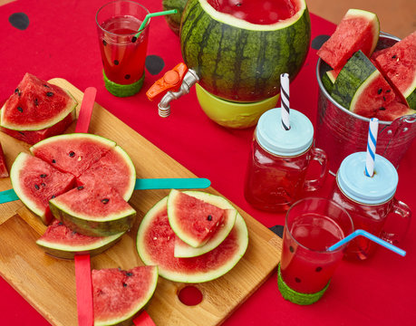 Close up summer outdoor table with red sheet and watermelon style drinks and slices for watermelon party