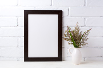 Black brown  frame mockup with grass and green leaves in pitcher vase
