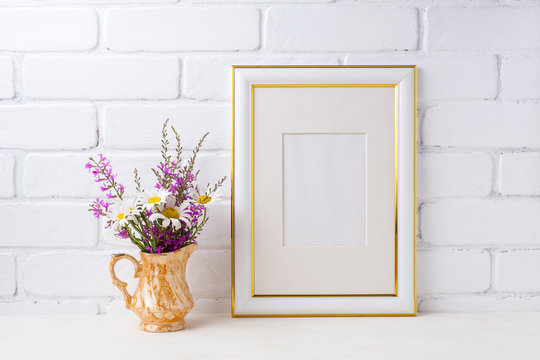 Gold decorated frame mockup with chamomile and purple flowers in golden pitcher