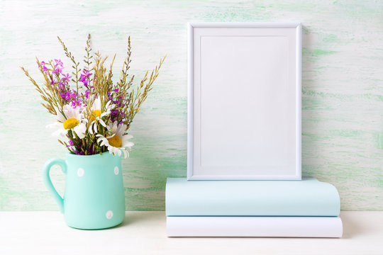 White frame mockup with chamomile and purple flowers in mint green pitcher and books