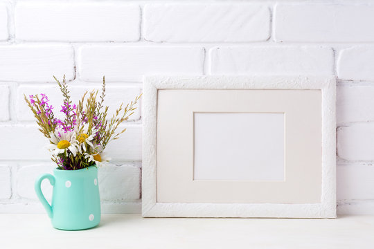 White landscape frame mockup with chamomile and purple flowers in mint green pitcher