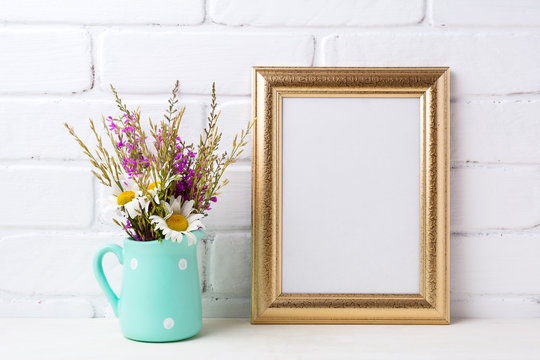 Golden  frame mockup with chamomile and purple flowers in mint green pitcher