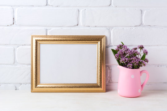 Golden  landscape frame mockup with purple flowers in pink rustic pitcher