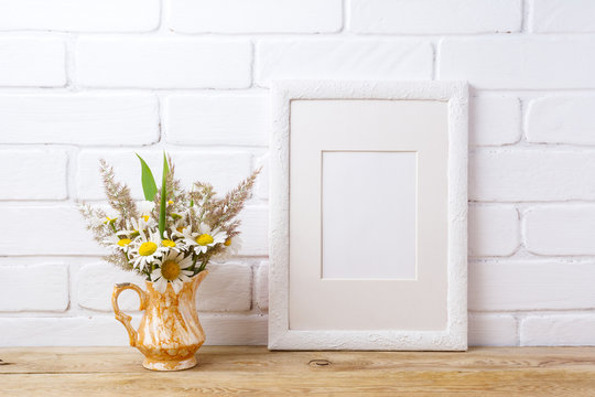 White frame mockup with chamomile and grass in golden vase