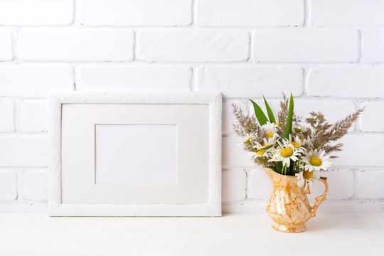 White landscape frame mockup with chamomile and grass in golden vase