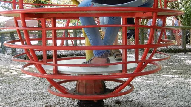 Enfants dans un parc sur un tourniquet rouge