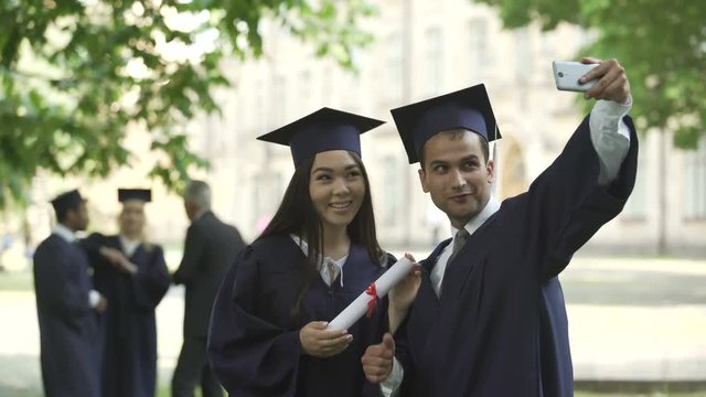 Classmates in graduation outfit taking selfie, convocation day, higher education