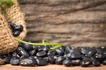 Black bean in burlap bag on old wooden background, close up ,concept of healthy protein power,select focus