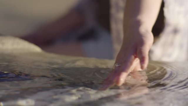 Closeup Of Young Woman's Hand Playing In Water, At A Fountain In A Public Square, Slow Motion, Beautiful Natural Light 