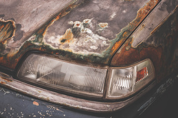 Headlight of a rusty old vintage white car