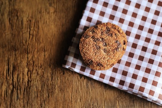 Top view of chocolate chip cookies on Scottish pattern napkins and on the wooden table.
