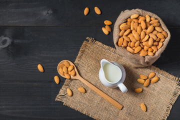 Almond milk in glass with almonds on  black wooden table