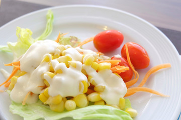 Salad of vegetables in a white plate on the table.