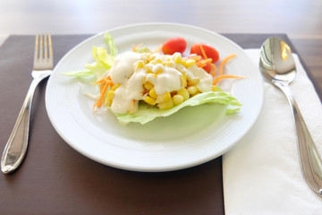 Salad of vegetables in a white plate on the table.