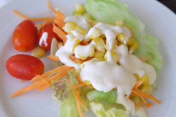 Salad of vegetables in a white plate on the table.