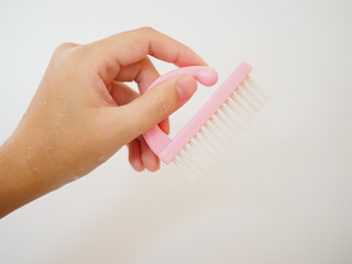 Left hand holding small pink cleaning brush, white background