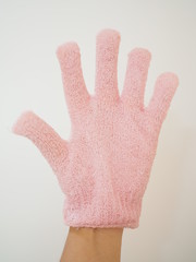 Left hand wearing pale pink scrubbing glove, on white background, vertical forehand