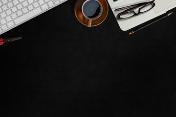 Modern dark surface office desk table with computer and office supplies.