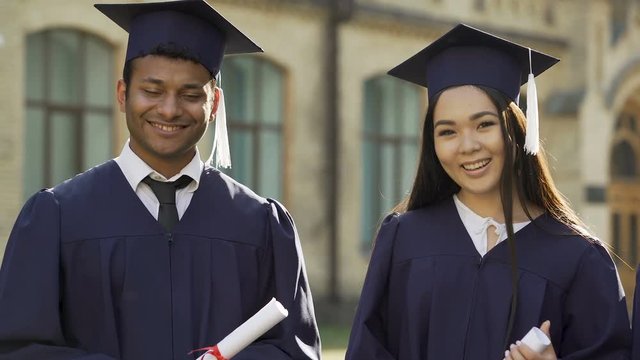 College student in graduation outfit with diplomas smiling, education abroad