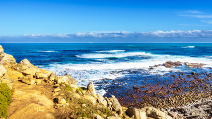 Fototapeta na wymiar Waves of the Atlantic Ocean breaking on the rocky shores of Cape of Good Hope in Cape Point Nature Reserve on the Cape Peninsula in South Africa