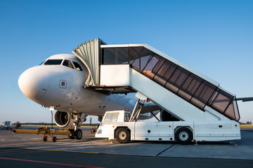Fototapeta na wymiar Passenger jet plane with boarding steps vehicle on the airport apron preparate for the departure