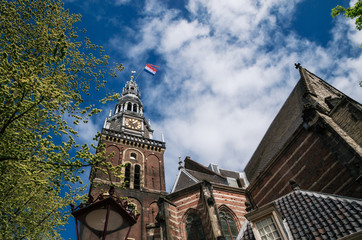 Fototapeta na wymiar Tower of the old church with dutch flag in the center of Amsterdam Netherlands