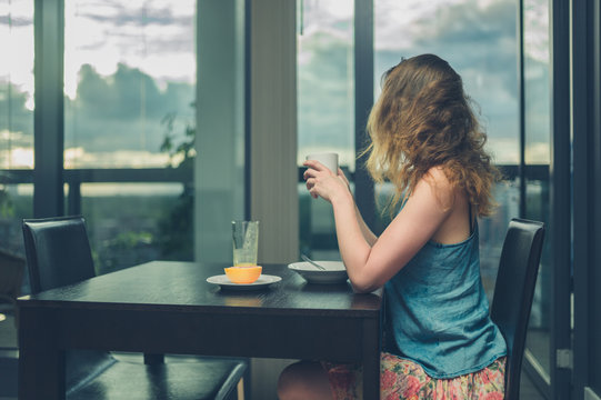 Young woman having breakfast by the window in the city