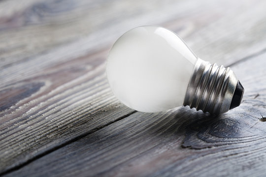 White light bulb glowing on wooden background, idea concept