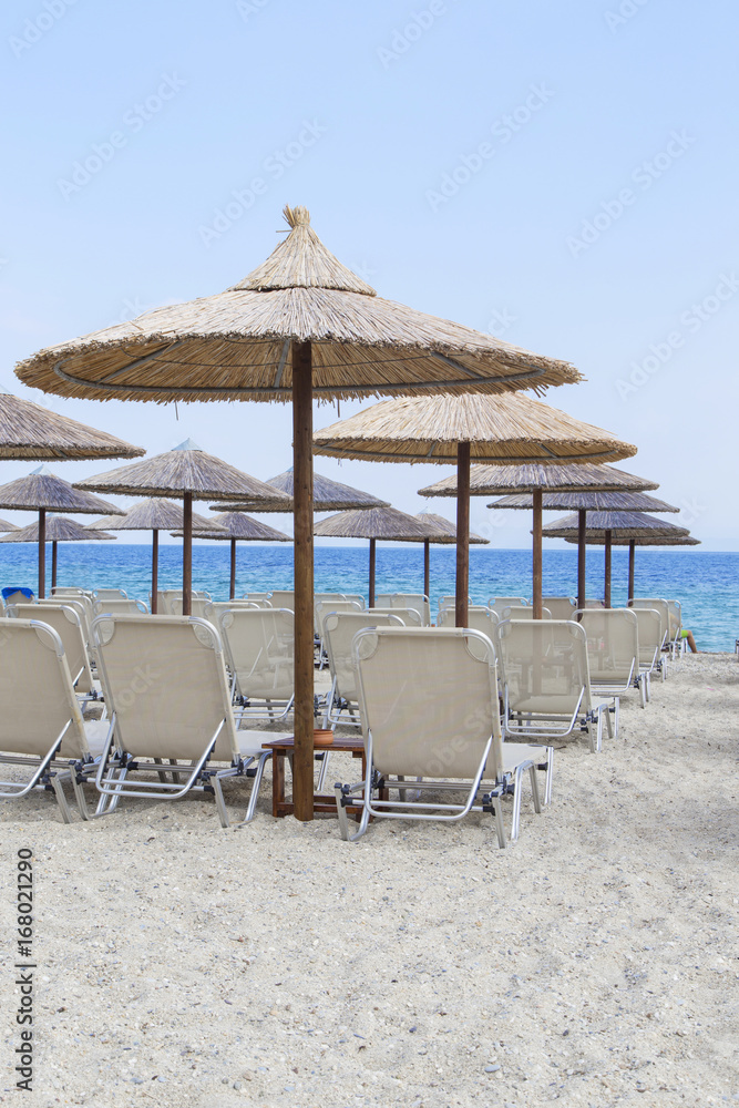 Poster Sun umbrella and beach beds on tropical coastline