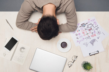 Young businessman sleeping on desk at workplace