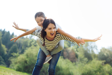 Joyful mother giving a piggyback to her little daughter