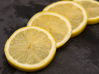 Four slices of lemon on slate wet stone