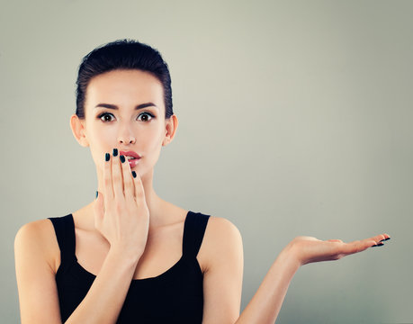 Happy Surprised Woman Woman Showing Empty Open Hand. Young Model with Empty Hand and Fashion Makeup on Banner Background