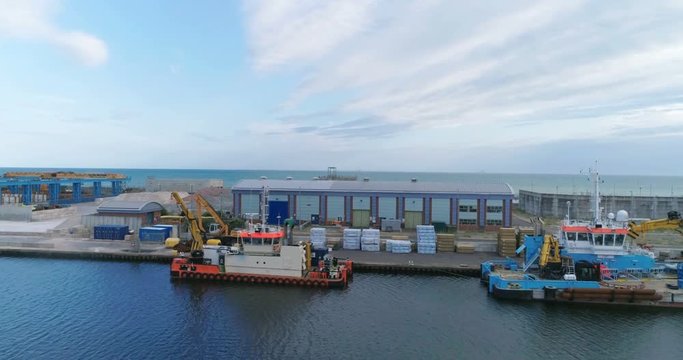 Aerial dolly view of boats and cranes in a commercial harbour in Southern England