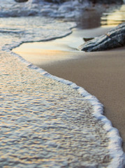 Wave of the sea on the sand beach. Seashore on sunset