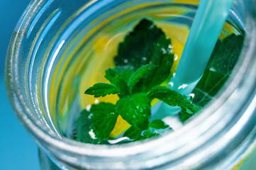 Glass mug with cold refreshing drink with lemon and mint.