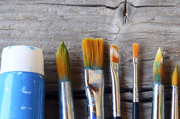 Paint brushes and paint on old wooden background.Set of artistic paintbrushes.Brushes for painting on a rustic table.Selective focus.