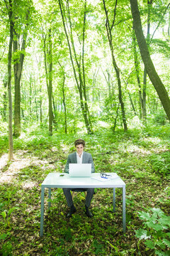 Young Handsome Business Man In Suit Working At Laptop At Office Table In Green Forest Park.