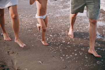 Fototapeta na wymiar Family legs with little daughter on the beach