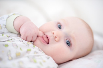 A baby sucking a finger with his tongue out