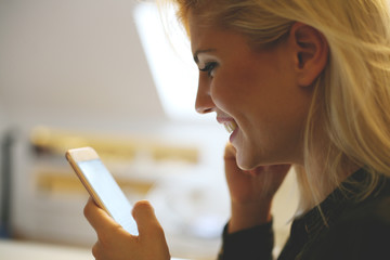 Young woman looking at her mobile phone. Smiling Caucasian woman typing on her mobile phone.