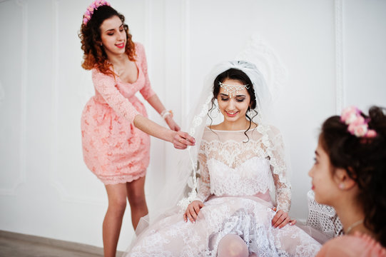Bridesmaids helping bride to put her wedding shoes on and get ready for her wedding.