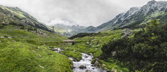 Panoramic view of the Fagaras mountains, water stream and famous Transfagarasan road in Carpathians, Romania, spectacular wilderness scenery