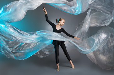 Girl in black clothes in the studio on the background of flying polyethylene film