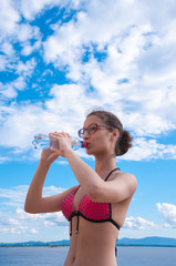 Girl wearing glasses in a bathing suit drinking water