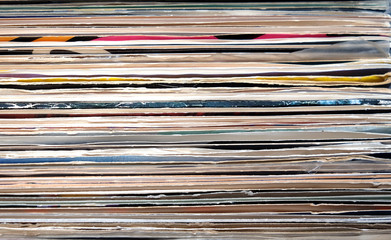 Horizontal pile of many close standing vinyl records covers as background front view close up