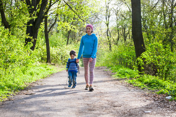 Fototapeta premium The boy and his mother are walking through the woods.
