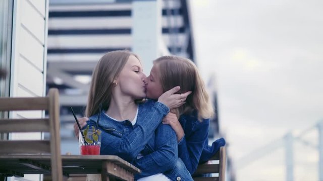 Mother kisses daughter outdoors